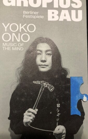 Proschüre mit Yoko Ono samt Hammer in der Hand auf dem Titel