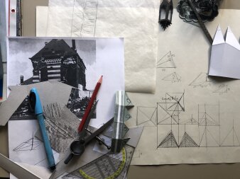 auf verschiedenen Skizzen und einem Fotoausdruck liegen ein Fineliner, ein Bleistift, ein Zirkel und ein Geodreieck