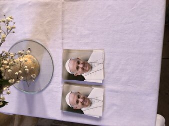 Zwei Fotos von einem Mann mit weißem Gewand und weißer Mütze auf einer weißen Tischdecke liegend