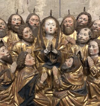 eine Heiligengruppe bestehend aus Figuren mit gefaltenten Händen und goldfarbenen Gewändern