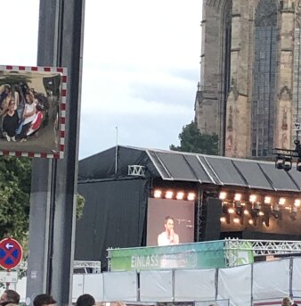Foto: Clueso finden die Freunde unserer Kinder toll © Vera Siemund Blick auf eine Bühne, davor ein Bauzaun und Köpfe verschiedener Personen
