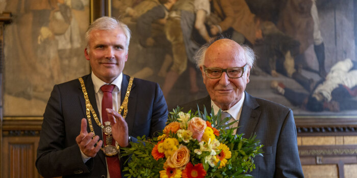 Zwei Männer bei der Ehrung zum Erfurter Ehrenbürger mit Blumenstrauß.