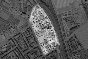 Ein Luftbild eines Industriekomplexes an einer Bahntrasse. Dieser ist farblich hervorgehoben.