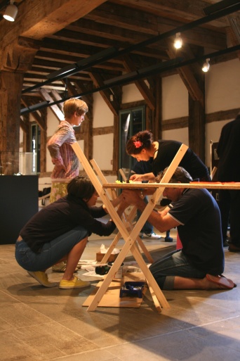 Zwei knieende und zwei stehende Künstler vor einer Installation.