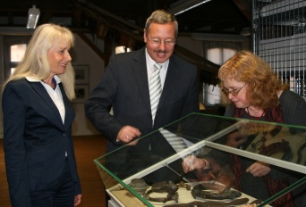 Drei Personen betrachten eine Vitrine der Ausstellung "Vormünzliche Zahlungsmittel"