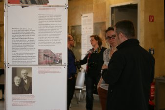 Rechts im Bild vier Personen, links eine Ausstellungstafel.