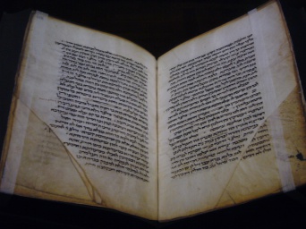 Ein aufgeschlagenes altes Buch mit hebräischen Text. Teile der Seiten fehlen.
