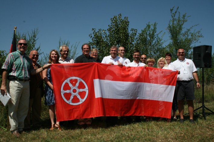 Vierzehn Personen hinter einer rot-weißen Fahne. Links auf der Fahne das Erfurter Rad.