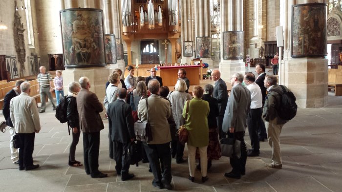 In der Kathedralkirche: Tagungsteilnehmer besichtigen die Pfeilerbilder im Katholischen Dom zu Erfurt Menschengruppe vor Rundbildern des Domes.