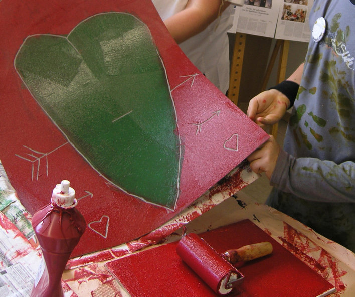 Farbig gestaltete Pappe mit grünem Herz auf rotem Grund.