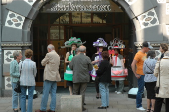 Personen vor einem alten Portal, z.T. mit Kopfschmuck.