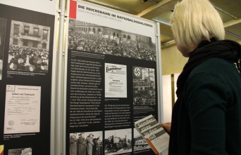 Eine blonde Frau schaut auf Ausstellungstafeln.