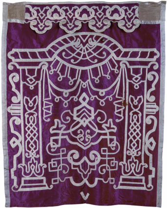 Foto: Parochet, auchToravorhang, Seidentaft mit Bandornamentik, um 1800 (Inv. Nr. S 26). Die hebräische Bezeichnung Parochet wurde von der Benennung des Jerusalemer Tempels übernommen. © Ulrich Fischer Karminroter Seidentaft-Parochet und Bändelwerk nach dem Muster des 70 n.Chr. zerstörten Tempels.