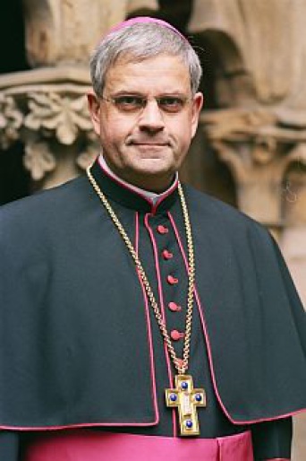 Weihbischof mit schwarzer Soutane, schwarzer Mozetta mit violetten Knöpfen, Zingulum, Brustkreuz und Zucchetto, auch Pileolus genannt.