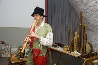 Herr mit Hut und Kostüm mit Flöte.