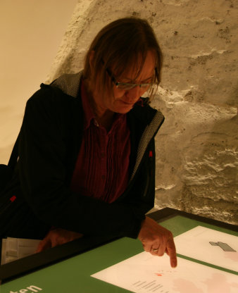 Foto: Dr. Karin Sczech, Thüringisches Landesamt für Denkmalpflege und Archäologie, erklärt neueste Befundergebnisse © Stadtverwaltung Erfurt Dame zeigt auf Vitrine.