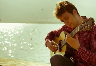 Foto: Sanel Redžić, Konzertgitarre, Weimar © Privat Junger Mann mit Gitarre am Wasser.