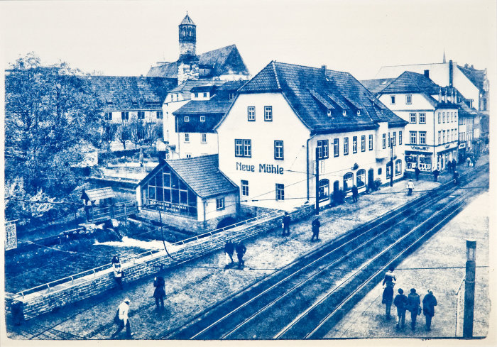 Neue Mühle Erfurt Großes Gebäude mit Krüppelwalmdach, daran ein Glasanbau. Im Vordergrund eine Brücke.