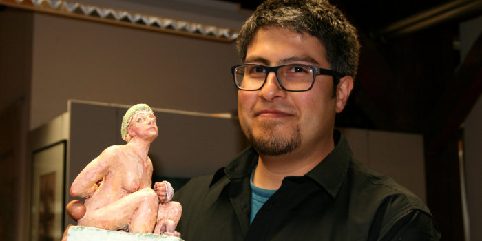 Ein junger Mann präsentiert eine kleine Skulptur.