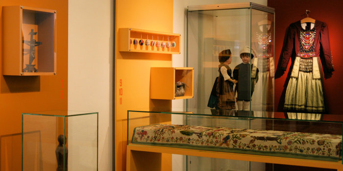 Farblich gestaltete Ausstellung in Rot- und Gelbtönen, inklusive Glasvitrinen.