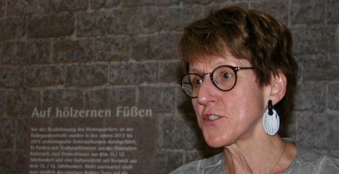 Foto: "Je Fundstelle nur ein Stück", Kuratorin Gudrun Noll-reinhardt will mit den Exponaten schlaglichtartig ein Fenster in die Vergangenheit öffnen © Stadtverwaltung Erfurt Eine Dame spricht vor einer Ausstellungspräsentation.
