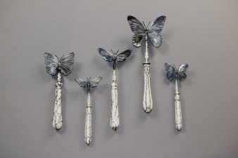 Fünf künstlerisch gestaltete Schmetterlinge auf Besteckstielen.