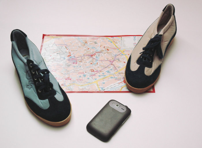 Denkmal-Fotocross zwei Sportschuhe stehen und ein Smartphone liegt auf einem Stadtplan