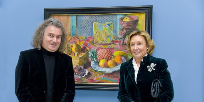 eine Dame rechts, ein Herr links, in der Mitte ein farbenfrohes Gemälde