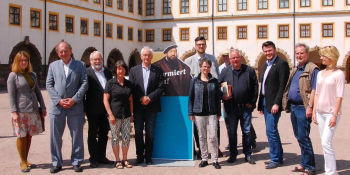Foto: Die Partner der "Wege zu Cranach" auf Schloss Friedenstein in Gotha © Geschäftsstelle „Wege zu Cranach“ Elf Personen in Reihe, dahinter das Schloss.