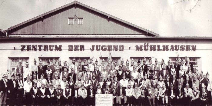 Große Karnevalsgruppe vor einem Gebäude.