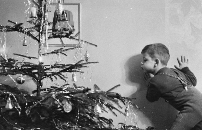 Schwarz-weiß Foto eines Kindes, das die Kerzen einen Weihnachtsbaumes auspustet
