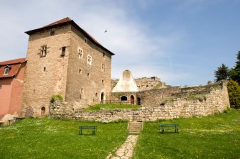 Im Vordergrund die Kernburg mit Kemenate, davor eine grüne Wiese, dahinter strahlend blauer Himmel