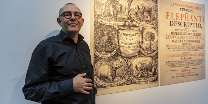 Ein Mann steht vor einer großen Tafel in einer Ausstellung