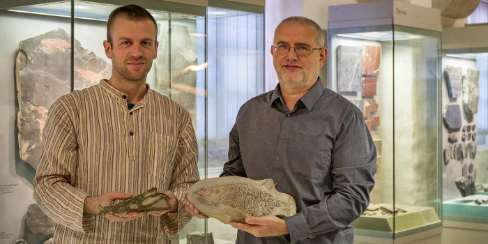 Zwei Männer halten zwei Fossilien in den Händen