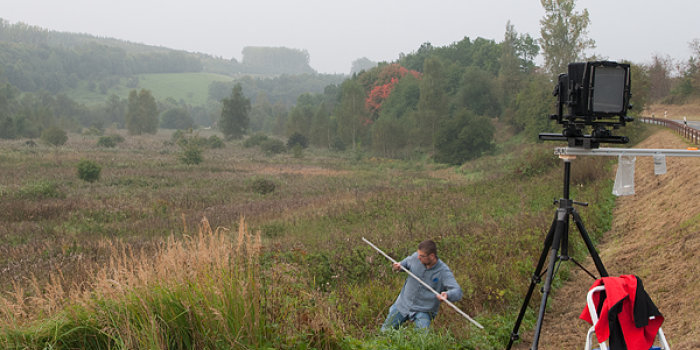 Foto: Foto zur Entstehung der Arbeit „Horizont“ © Richard Welz Ein Mann steht mit einem Stab im Feld