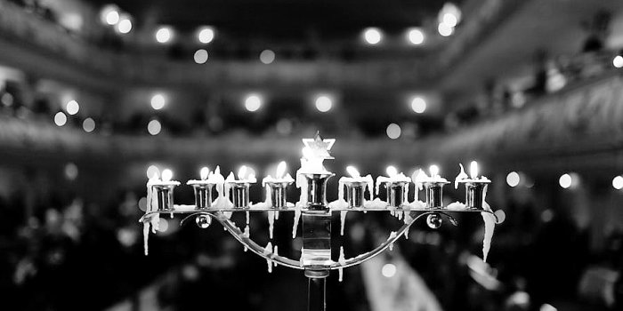 Schwarz-weiß Foto eines Chanukka-Leuchters, auf dem alle acht Kerzen brennen
