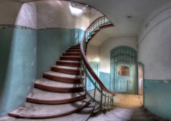 Ein Treppenaufgang: Das Holz der Treppe geht kaputt, an den Wänden fällt der Putz ab