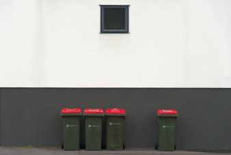 Drei Mülltonnen stehen nebeneinander, eine vierte mit deutlichem Abstand daneben