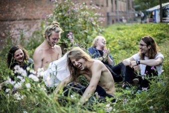 Fünf Jugendliche sitzen im Gras und lachen