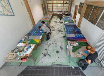 Vier Menschen arbeiten an den Platten mit Glasfliesen