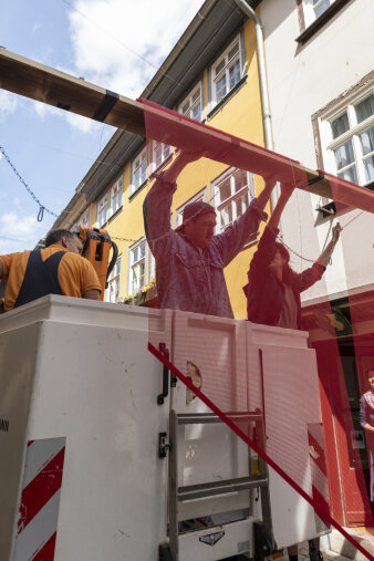 Zwei Menschen hängen rote Elemente an ein Seil