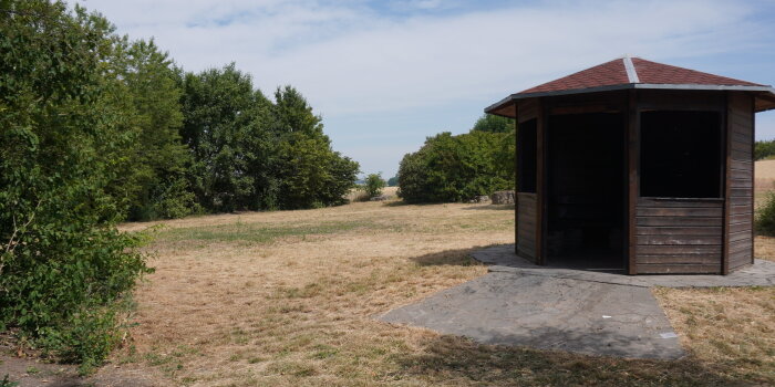 Eine Wiese mit einer kleinen Hütte und Bäumen