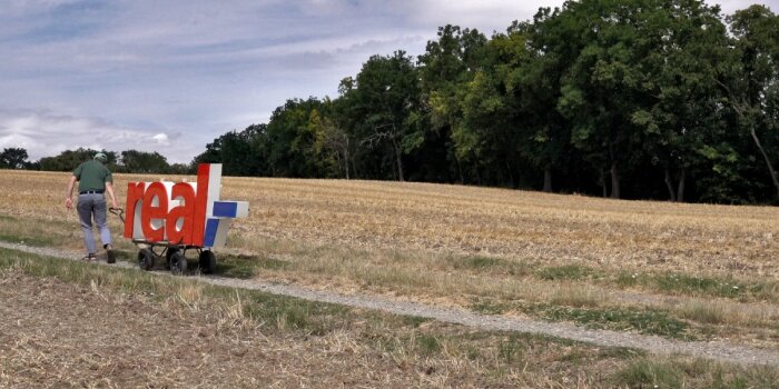 ein Mann zieh eine real-Leuchtreklame über ein Feld