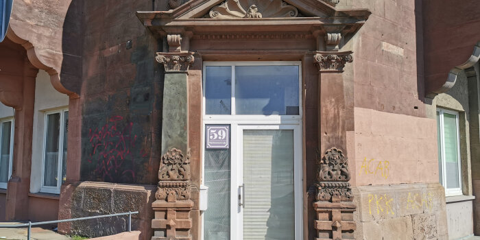 Eingang im Eckgebäude im neoklassizistischen Stil eines Gründerzeitbaus, aus roten Sandsteinblöcken errichtet 