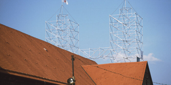 das Dach der Peterskirche und zwei Gerüsttürme symbolisieren deren ehemalige Türme