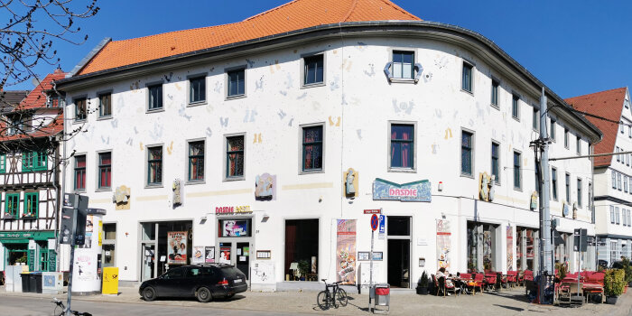 Das große und weiße Eckgebäude mit seinen markanten Symbolen auf der Fassade und dem Schriftzug DasDie über der Tür