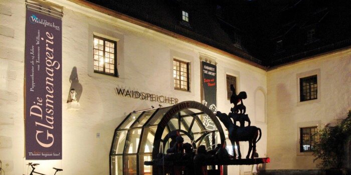 Foto: Theater Waidspeicher Außenansicht © Stadtverwaltung Erfurt ein Gebäude aus Stein mit Beleuchtung am Abend