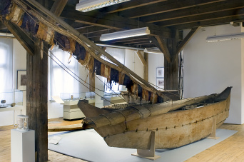 Ein Boot aus Holz, im Hintergrund Vitrinen.
