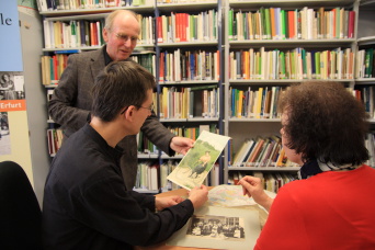 Foto: Beratungssituation in der Dokumentationsstelle © Stadtverwaltung Erfurt Beraterin und Berater zeigen dem Kunden Fotos