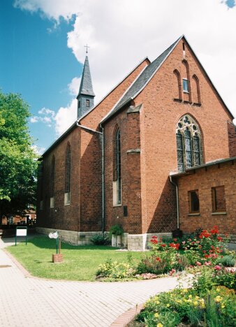 Backsteinkirche, im Vordergrund grüne Anlage.